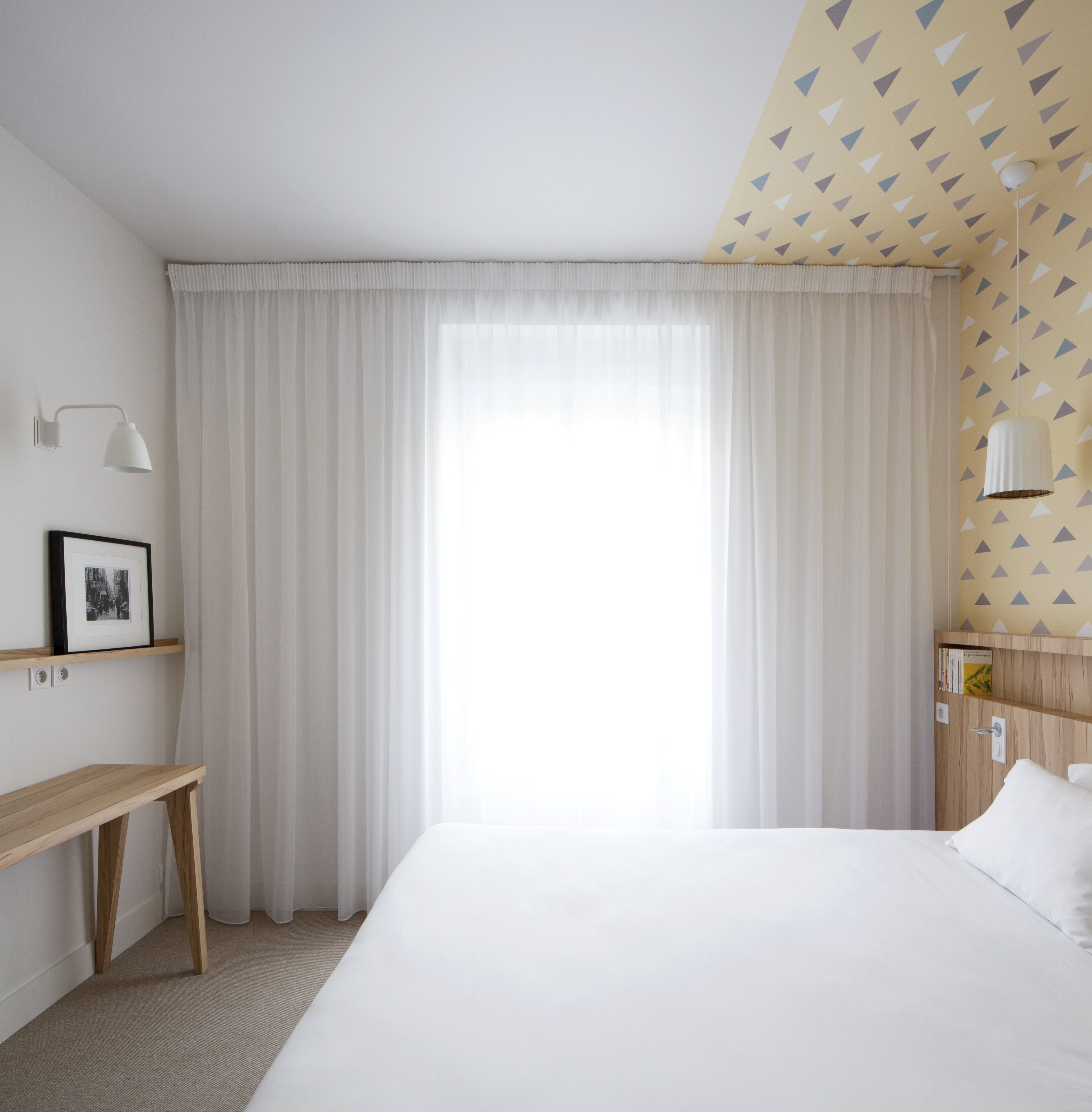 Habitación de hotel con una cama grande, una mesita de noche, un escritorio, una lámpara y un armario.