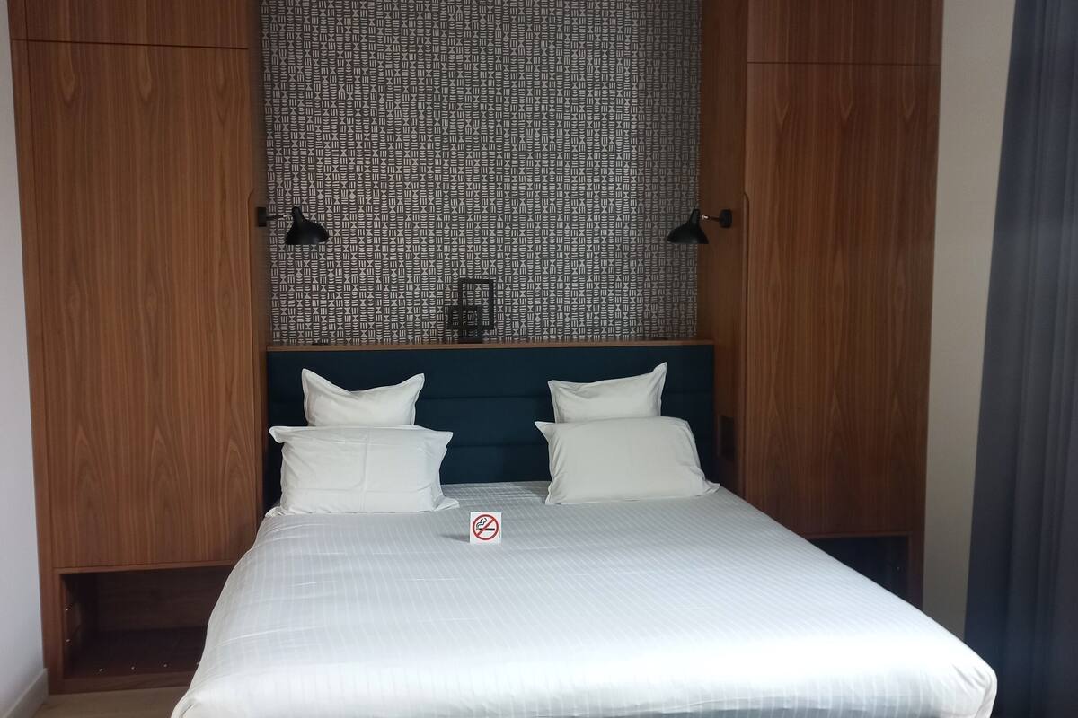 Un dormitorio con cama, un banco y armarios de madera.