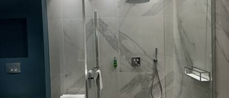 Une salle de bain moderne dotée d’une douche à parois de verre, de toilettes et d’un lavabo.