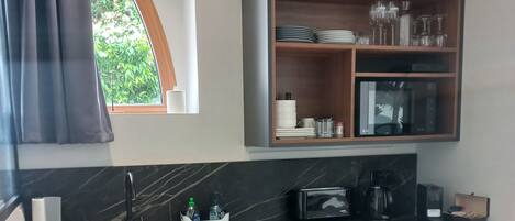 Una cocina moderna con microondas integrado, un lavamanos y una encimera de madera.
