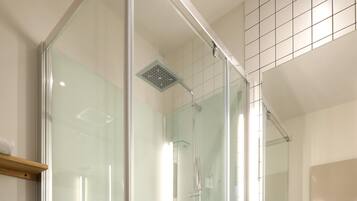 A modern bathroom with a glass-enclosed shower, a white sink, and a wooden vanity.
