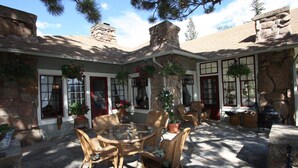 A stone building with a patio area featuring wicker furniture and potted plants. - Beautiful Setting, Romantic Historic Arts & Crafts Home, Great Longs Peak Views (Estes Park)