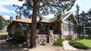 A stone house with a stone chimney, a porch with a stone railing, and a stone staircase leading to the front door. - Beautiful Setting, Romantic Historic Arts & Crafts Home, Great Longs Peak Views (Estes Park)