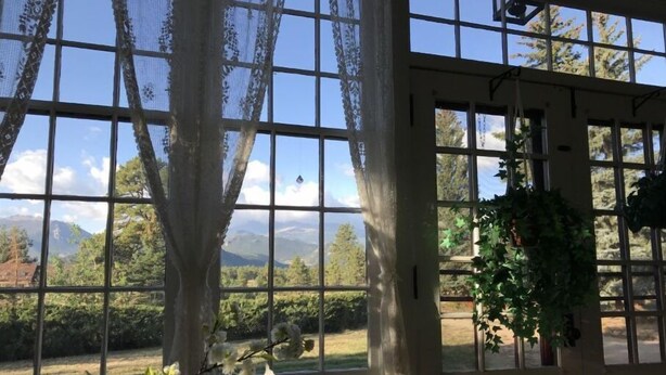 A room with large windows, lace curtains, and a view of mountains. - Beautiful Setting, Romantic Historic Arts & Crafts Home, Great Longs Peak Views (Estes Park)