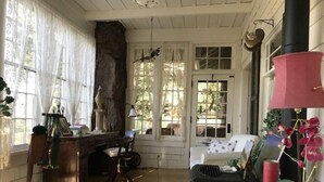 A cozy room with a wooden desk, a comfortable chair, a bed with floral bedding, and a red lamp. - Beautiful Setting, Romantic Historic Arts & Crafts Home, Great Longs Peak Views (Estes Park)