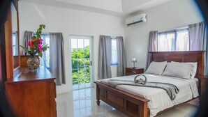 A bedroom with a bed, bedside table, lamp, and a vase with flowers.