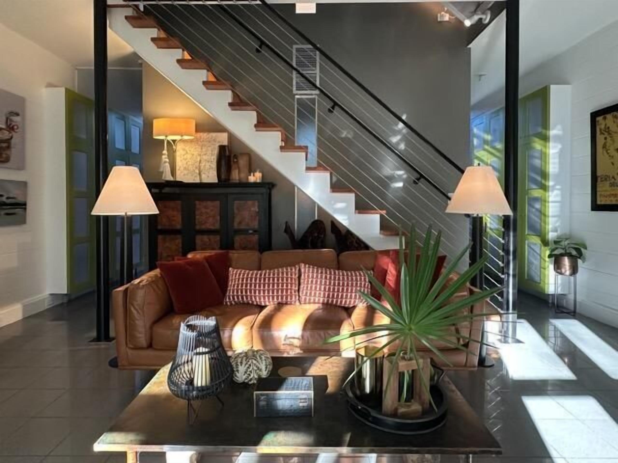 A modern living room with a staircase, a sofa set, and two floor lamps.