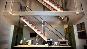 Une cuisine moderne dotée d’un îlot central, d’un escalier à double révolution et d’une grande fenêtre laissant entrer la lumière naturelle.