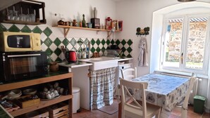 A compact kitchen with a microwave, oven, and a small dining table. - The house under the stars (Sembadel)