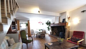 A cozy living room with a fireplace, a dining area, and a staircase. - The house under the stars (Sembadel)