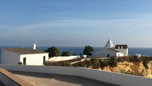 Una propiedad costera con edificios blancos, una estructura destacada de color blanco con techo cónico, y vista al mar.