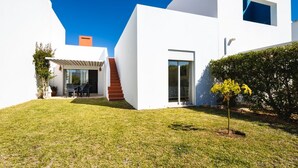 Una casa moderna con fachada blanca, un porche cubierto y un pequeño jardín.