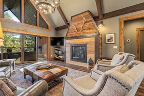 A spacious living room with a fireplace, leather furniture, and a large window overlooking a deck.