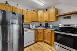 A kitchen with wooden cabinets, stainless steel appliances, and a microwave.