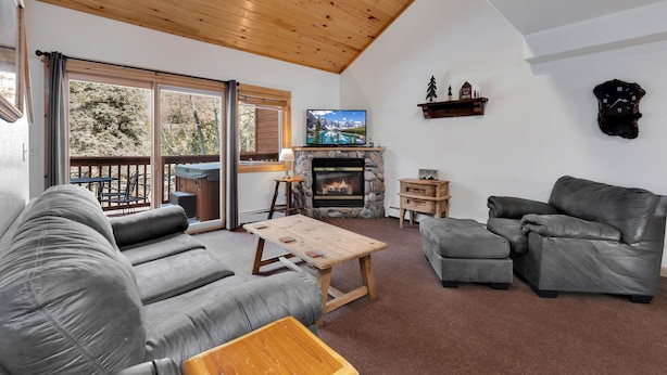 Ein gemütliches Wohnzimmer mit Kamin, Ledersofas, einem Holztisch und einem Fernseher.