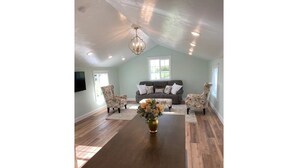 A spacious room with a wooden dining table, floral armchairs, a sofa with patterned cushions, and a chandelier. - Heavensfield - Family Reunion Center (Rexburg)