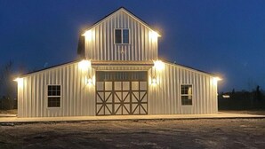 A large, single-story barn with a gabled roof and a garage door. - Heavensfield - Family Reunion Center (Rexburg)