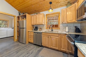 A kitchen with wooden cabinets, stainless steel appliances, and a granite countertop. - Fall River Oasis • Private Hot Tub • RMNP (Estes Park)