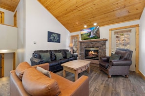 A cozy living room with a fireplace, leather sofas, and a stone fireplace surround. - Fall River Oasis • Private Hot Tub • RMNP (Estes Park)