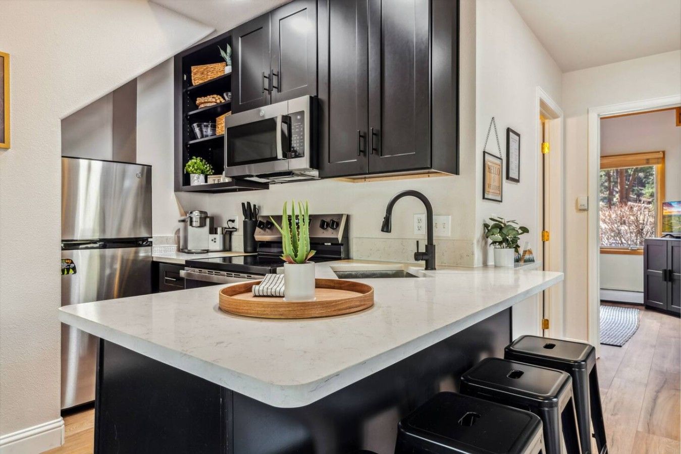 Una cocina moderna con armarios oscuros, electrodomésticos de acero inoxidable y una isla central con taburetes.