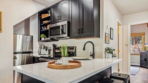 A modern kitchen with dark cabinets, stainless steel appliances, and a central island. - Fall River Suite • River Views • Near RMNP (Estes Park)