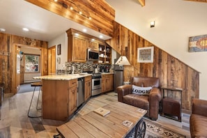 Una cucina rustica con mobili in legno, un'isola centrale e una zona pranzo con poltrone in pelle.