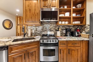 A kitchen with wooden cabinets, a stainless steel stove, and a microwave. - Fall River Suite • Serene • Close to RMNP (Estes Park)
