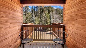 A wooden deck with two chairs and a railing, overlooking a forested area. - Fall River Suite • Serene • Close to RMNP (Estes Park)