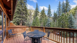 A wooden deck with a round table and chairs, surrounded by a wooden railing.