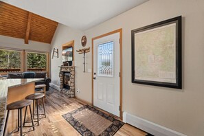A cozy interior with a stone fireplace, a dining area with bar stools, and a large framed map on the wall. - Peaceful Fall River Suite • Minutes to RMNP (Estes Park)