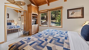 A bedroom with a large bed, wooden ceiling beams, a wardrobe, and a view of the outdoors. - Peaceful Fall River Suite • Minutes to RMNP (Estes Park)