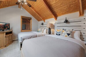 A bedroom with two beds, a television, a wooden headboard, and a ceiling fan. - Riverfront Haven • River Views • Near RMNP (Estes Park)
