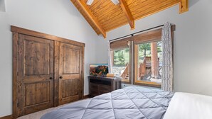 A bedroom with a large bed, wooden wardrobe, and a television. - Riverfront Haven • River Views • Near RMNP (Estes Park)