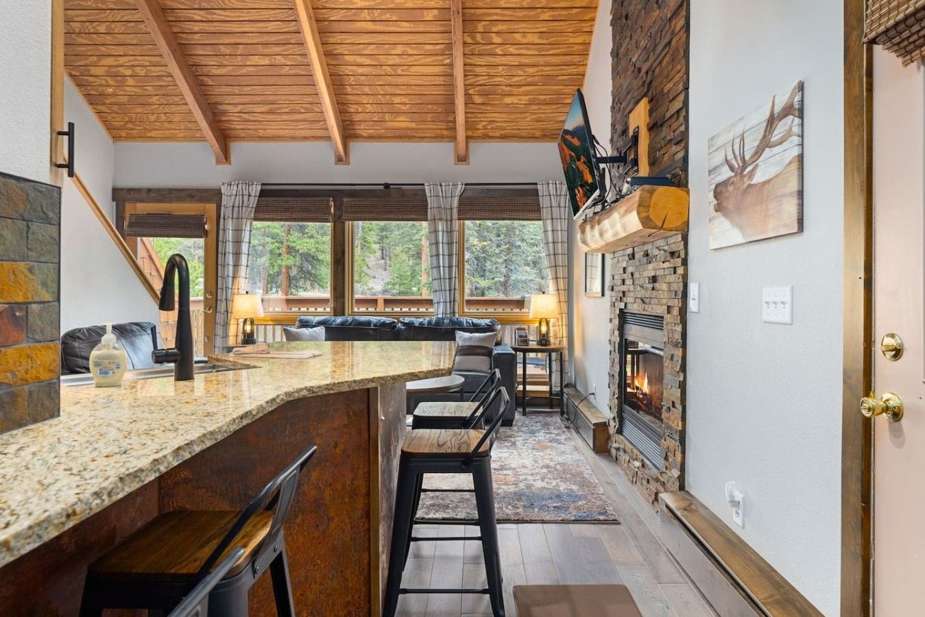 Una cocina con chimenea de piedra, vigas de madera en el techo y vistas al exterior.