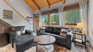 A cozy living room with a leather sofa, a round coffee table, and a fireplace. - Riverfront Haven • River Views • Near RMNP (Estes Park)