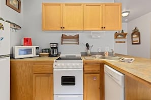 Una cocina funcional con armarios de madera, microondas, estufa y lavavajillas.