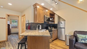 A modern kitchen with wooden cabinets, a granite countertop, and stainless steel appliances. - Quiet Fall River Suite • Fireplace • Close to RMNP (Estes Park)