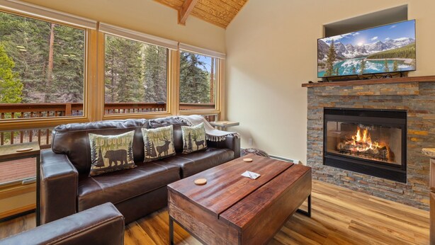 A cozy living room with a fireplace, large windows, and a comfortable seating area. - Quiet Fall River Suite • Fireplace • Close to RMNP (Estes Park)