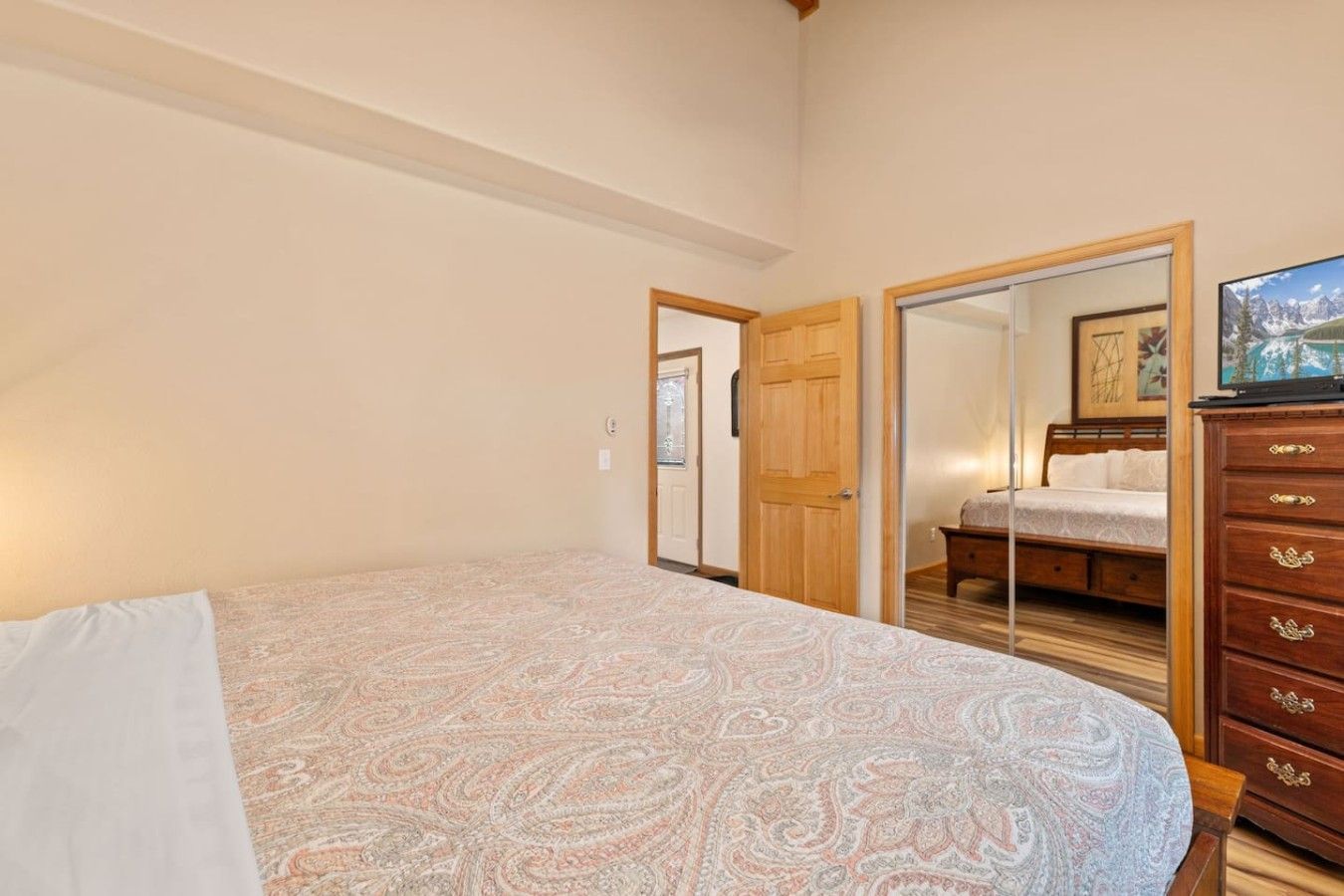 Un dormitorio con una cama, un aparador de madera y una televisión.