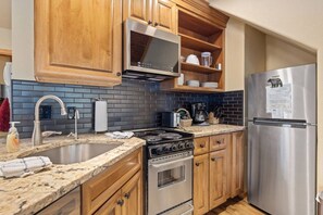 A kitchen with wooden cabinets, a stainless steel refrigerator, a microwave, a stove, and a sink. - Quiet Fall River Suite • Fireplace • Close to RMNP (Estes Park)