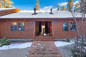 A wooden cabin with a wooden deck leading to the entrance, surrounded by snow and trees. - Riverside Sanctuary • RMNP • River Views (Estes Park)