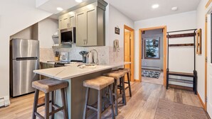 A modern kitchen with a stainless steel refrigerator, a microwave, and a large island with bar stools. - Riverside Sanctuary • RMNP • River Views (Estes Park)