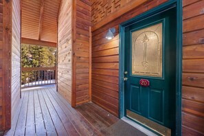 Une cabane en bois avec une porte verte portant le numéro « 20 » et un balcon doté d’une balustrade.