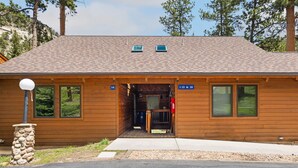 Un chalet en bois avec un toit en pente, deux fenêtres à l’avant et un pilier en pierre.