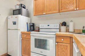 Eine kleine Küche mit Kühlschrank, Mikrowelle, Kaffeemaschine und Herd.