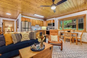 A cozy interior with a sofa, a wooden dining table, and a kitchen area. - Fall River Retreat • Private Hot Tub • Near RMNP (Estes Park)