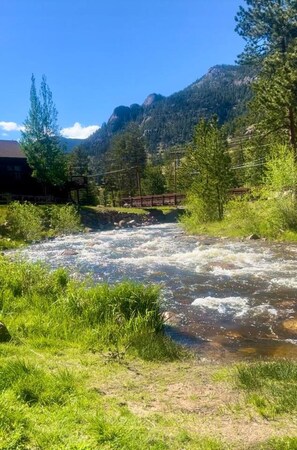A river flowing through a valley with a bridge and mountains in the background. - Fall River Retreat • Private Hot Tub • Near RMNP (Estes Park)