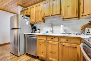 Una cocina con armarios de madera, electrodomésticos de acero inoxidable y salpicadero de azulejos.