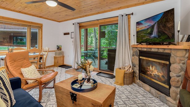 A cozy living room with a fireplace, comfortable seating, and a large TV. - Fall River Retreat • Private Hot Tub • Close to RMNP (Estes Park)