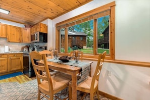 A wooden interior with a dining area, kitchen, and large windows. - Fall River Retreat • Private Hot Tub • Near RMNP (Estes Park)